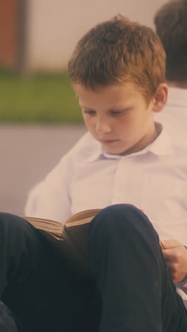 schoolboys tired of preparing for important tests and little girl with ponytail after lessons sitting on street pavement