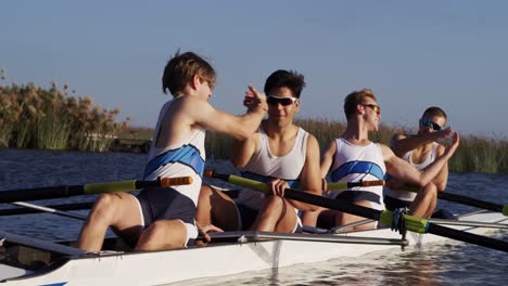 Side-view-of-male-rower-team-celebrating-on-the-lake