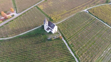 Drone-Aéreo-Sobre-Una-Iglesia-Medieval-En-Medio-De-Los-Viñedos-En-Otoño-En-Tirol-Del-Sur