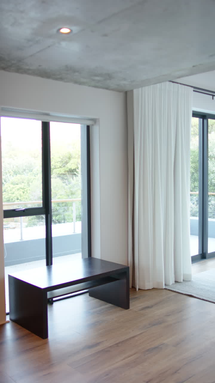 Vertical video: Modern bedroom with large windows and white curtains, offering serene view