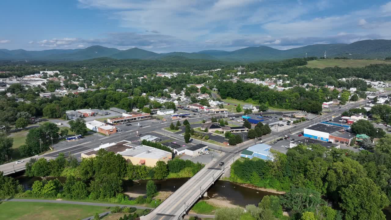 Two main streets of American town during sunny.l day in summertime. Green mountain landscape in distance. Aerial wide shot. Traffic scene on roads. Virginia, USA