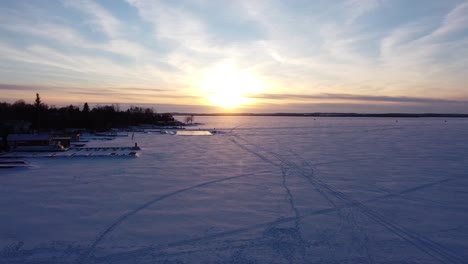 Cottage-Docks-Und-Eishockeybahn-Auf-Schneebedeckten-Zugefrorenen-Seen-Mit-Sonnenuntergang-Im-Winter