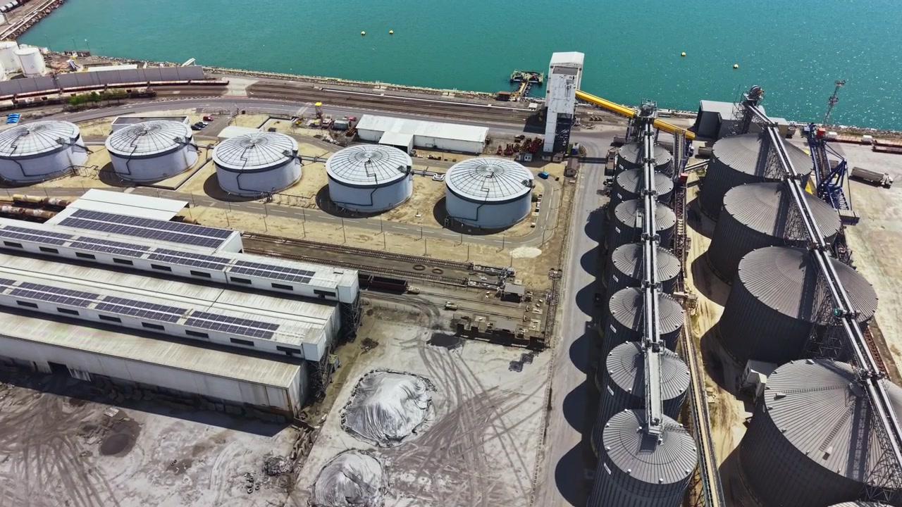 Industrial site with storage tanks and silos near water during daytime