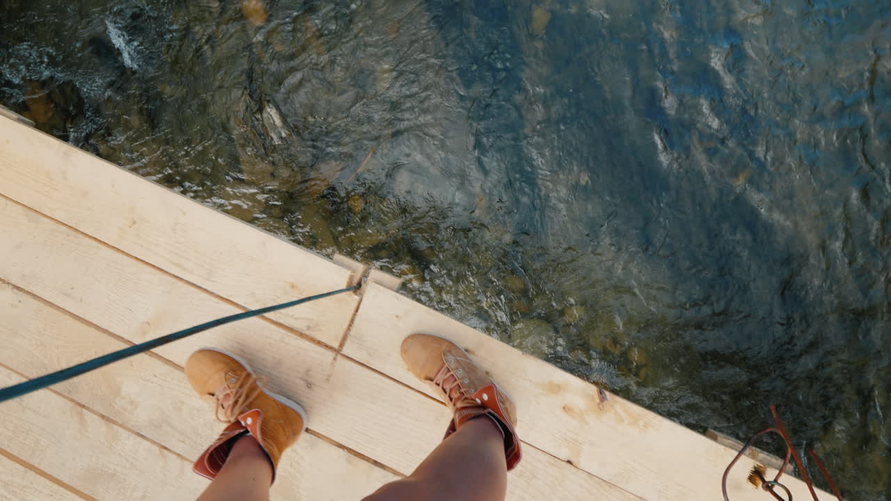 트레킹 부츠를 신은 남자가 벼랑 위의 나무 다리 가장자리를 따라 걷는다. pov 비디오