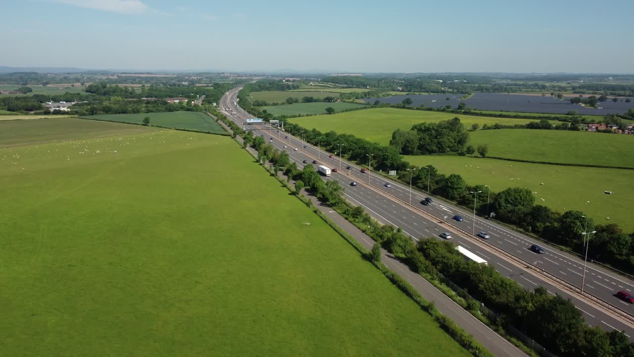Aerial view of a highway passing through a green countryside landscape with solar panels