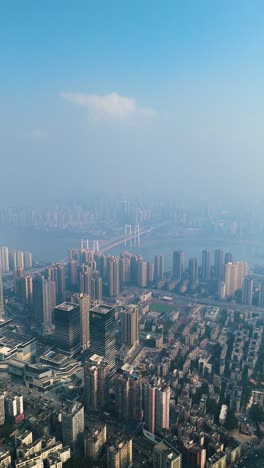 vertical aerial view of chongqing city shrouded in extreme pollution and smog, capturing the dense urban landscape, high-rise buildings, and the river fading into the haze. china