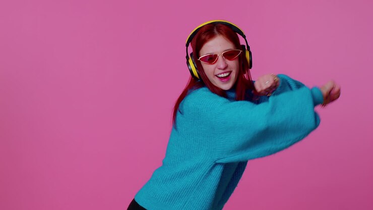 Cheerful attractive girl listening music via headphones and dancing disco fooling around having fun