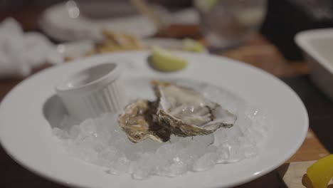 raw oysters on plate on ice in restaurant with blurred background