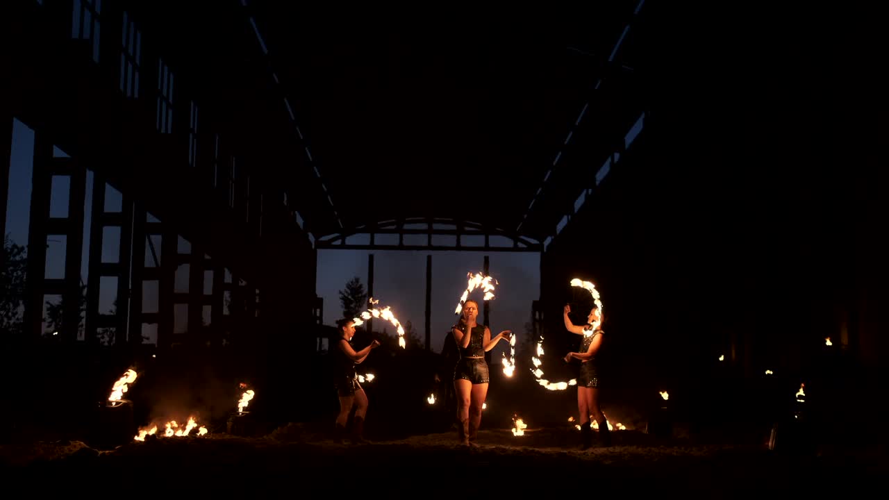un grupo de artistas profesionales con fuego muestran el espectáculo haciendo malabarismos y bailando con fuego en cámara lenta.
