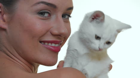 portrait of smiling beautiful woman with white kitty on white studio background