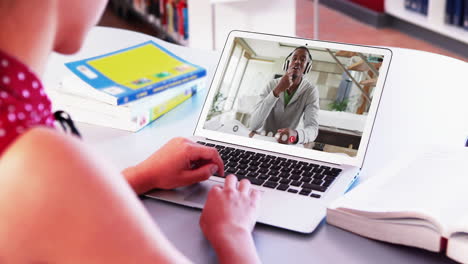 mujer de negocios caucásica sentada en un escritorio usando una computadora portátil haciendo una videollamada con un colega masculino