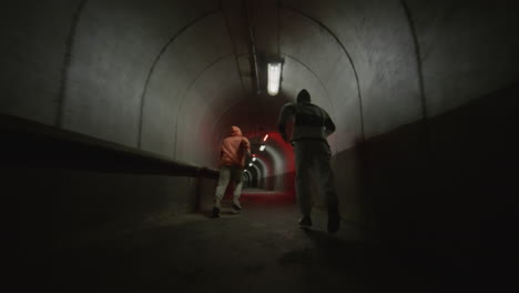 two boys freerunning and doing parkour flips in tunnel