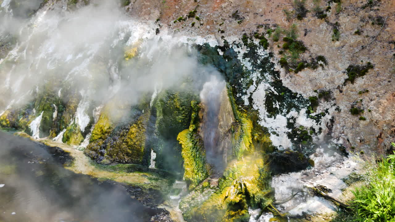toma panorámica de géiser de agua hirviendo con colores tropicales y pared de acantilado - waimangu, nueva zelanda