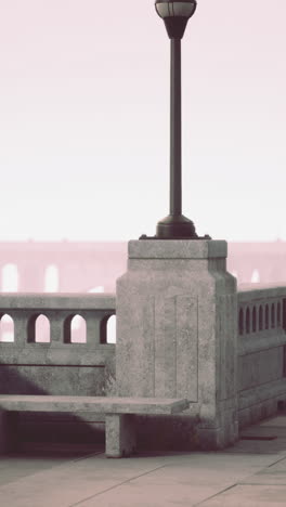 a stone bench with a lamp post on a concrete walkway