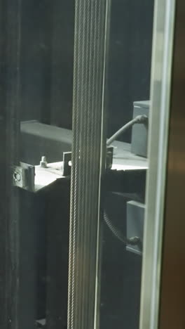 vista en primer plano de los mecanismos internos de un pozo de ascensor, mostrando los cables y la maquinaria en detalle
