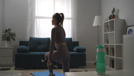 young woman with nice figure is doing squats with dumbbells at home exercises for keeping fit and losing weight healthy lifestyle and wellness