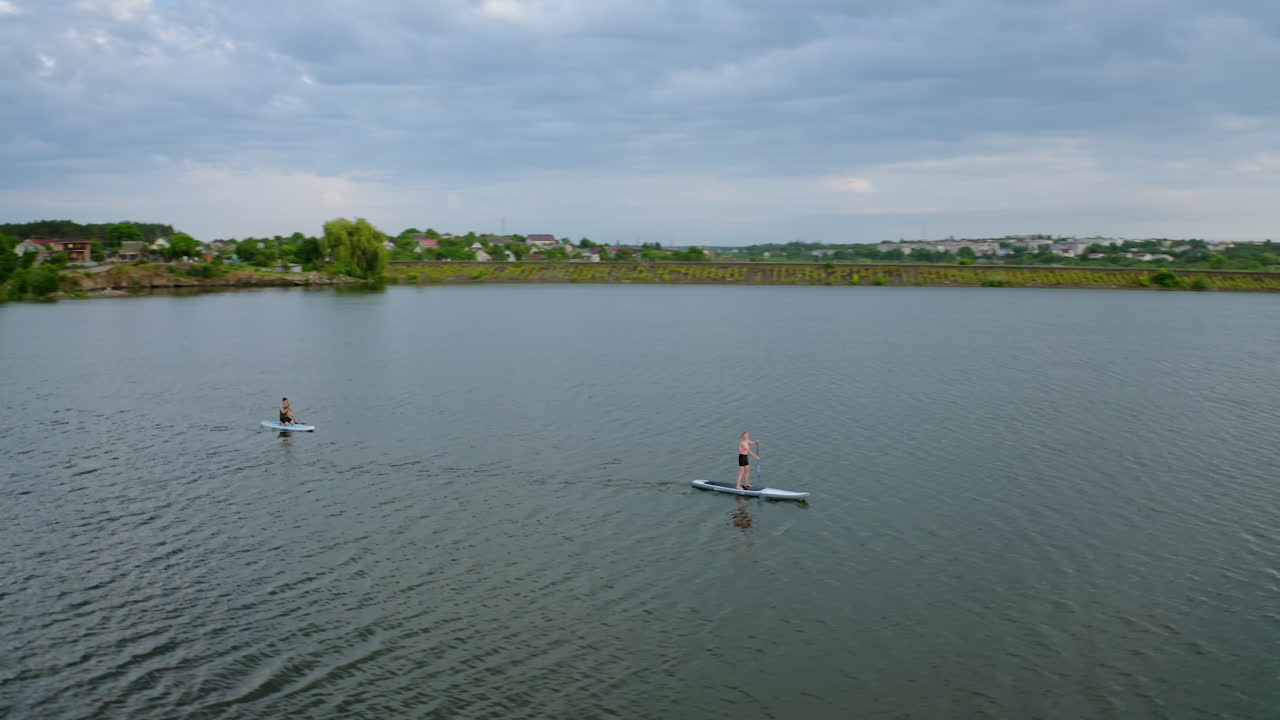 Young people doing sport on water. Travelling on boards on river on beautiful summer landscape in the countryside. Leisure time in summer. Aerial view.