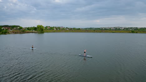 young people doing sport on water. travelling on boards on river on beautiful summer landscape in the countryside. leisure time in summer. aerial view.