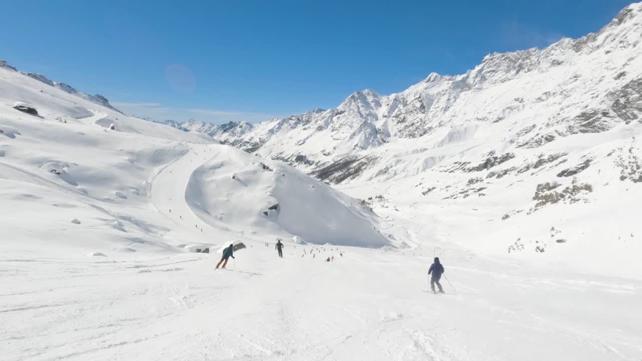 movimiento lento de los esquiadores pasan esquiando rápido cuesta abajo en una pista en la estación de esquí de cervinia alpes italianos en un día soleado