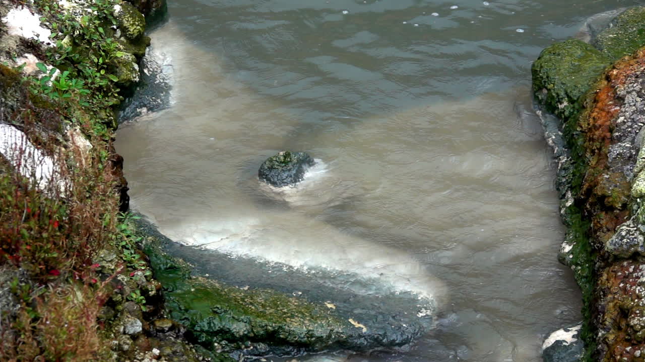 광물 퇴적물과 해조류로 착색된 암석에 대한 온천수 세척의 슬로우 모션 샷