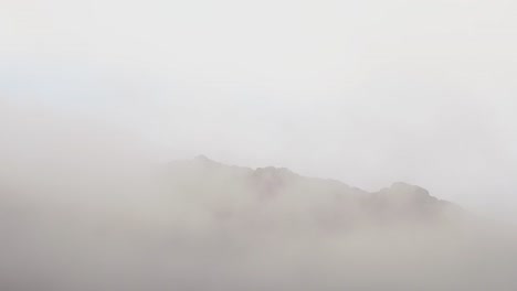 Wide-shot-showing-silhouette-of-mountain-during-dense-fog-and-mist-on-top