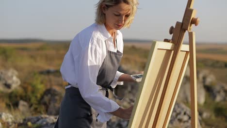 girl artist paints a picture at sunset in the countryside. - girl artist paints a picture at sunset in the countryside