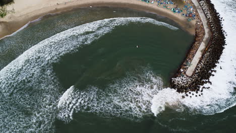 people surfing in sealinks beach while big waves are rooling at the beach and smashing on the breakwaters in vietnam