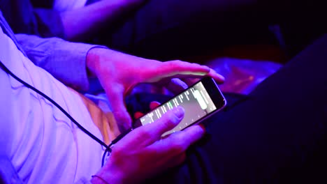 Man-looks-at-song-list-on-smart-phone-close-up