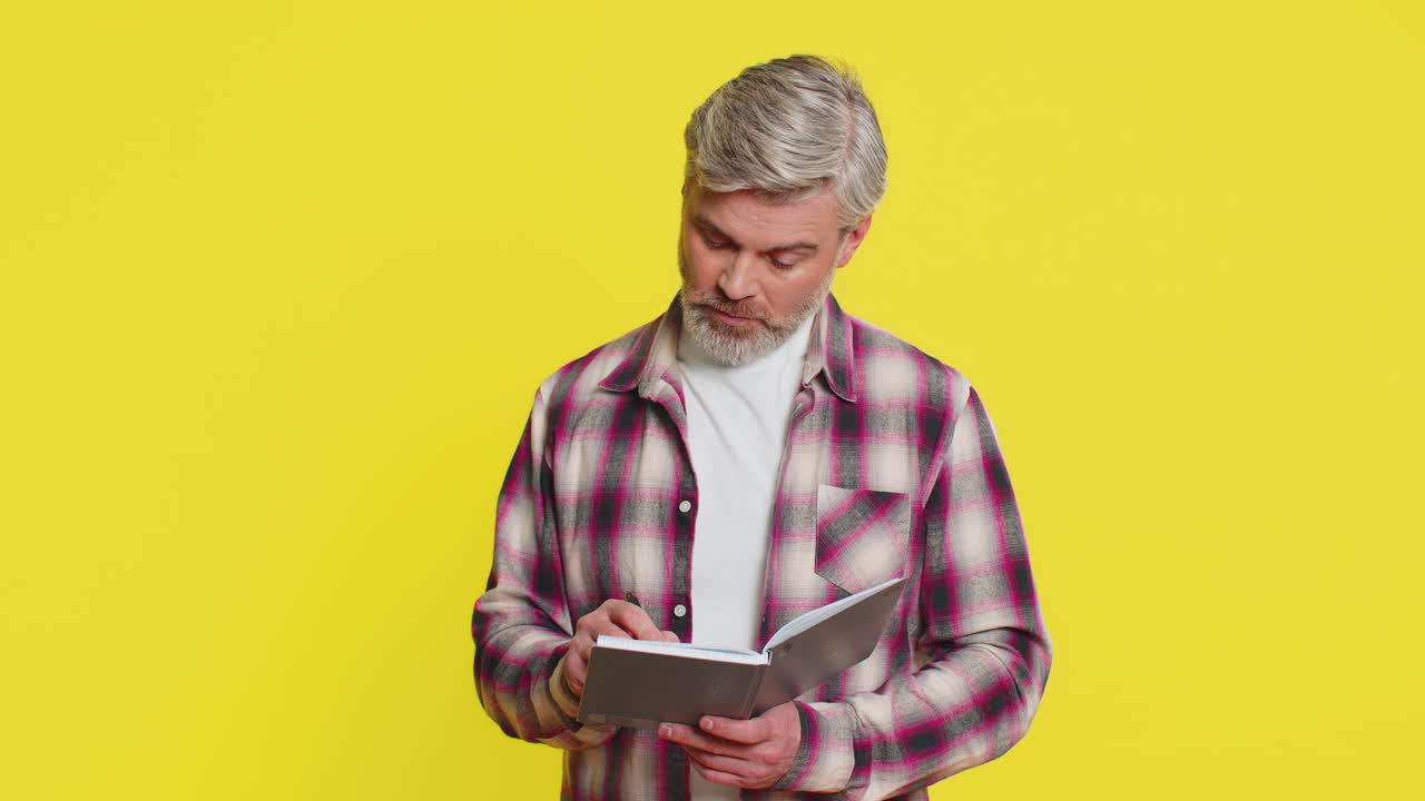 Mature man making notes writing thoughts with pen into notepad notebook diary to do list good idea