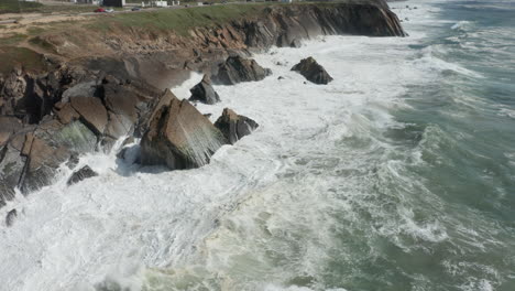 aerial of wild waves splashing on rocky cliffs