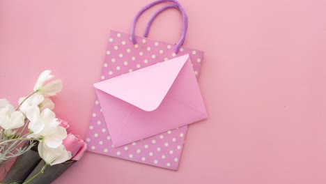 pink gift bag, envelope, and flowers
