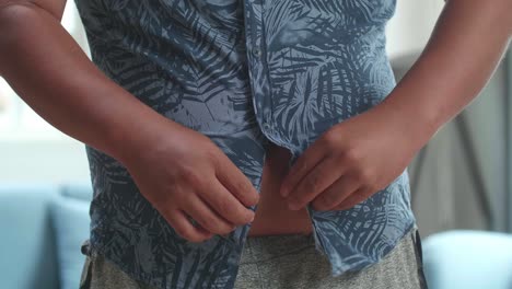 un hombre gordo con grasa en el vientre abotonando su camisa