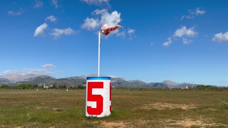 Bandera-De-Dirección-Del-Viento-Que-Sopla-Con-Viento-Fuerte-En-El-Aeródromo-Contra-El-Cielo-Azul