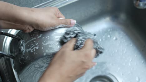 washing a pot in the kitchen sink