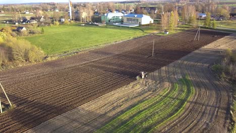 tractor plowing agricultural farm fields. aerial approaching view