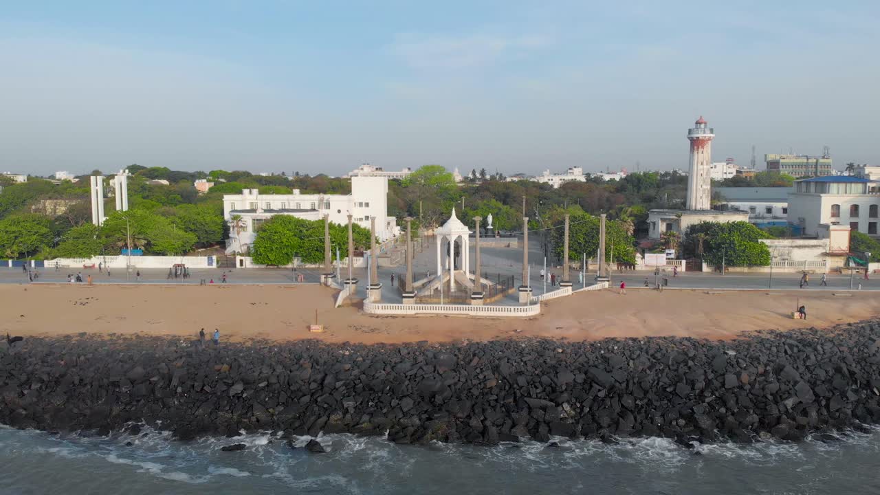 toma orbital aérea de derecha a izquierda de la estatua de mahatma gandhi cerca de las costas de la playa de rocas de pondicherry mientras la gente caminaba por la mañana, filmada con un dron en 4k