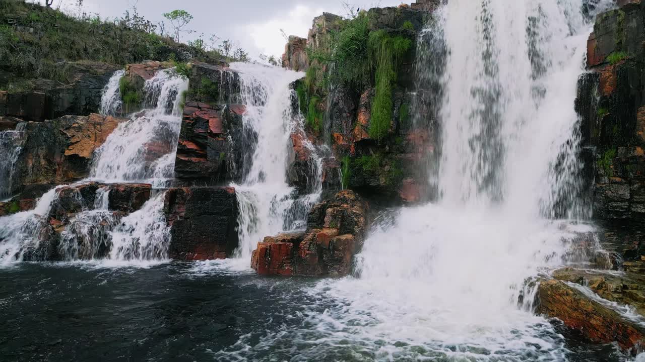 el agua fluye sobre las rocas rojizas de la cascada de couros en el parque nacional de chapada dos veadeiros, creando un hermoso espectáculo natural en el centro de brasil.