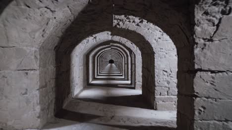 stone archway corridor stretching into shadowy distance, architectural lines converging with soft daylight filtering through historic masonry, revealing architectural depth and mystique