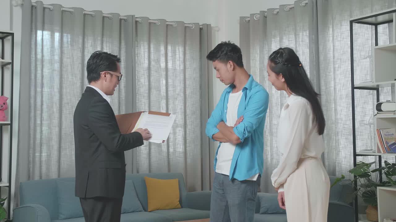아시아의 부동산 중개인이 집을 매입하는 계약에 대해 한 부부에게 설명하고 있습니다.