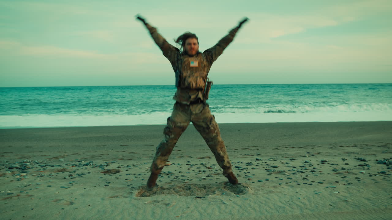 Un soldato della Marina americana esegue un jumping jack sulla spiaggia vicino all'oceano