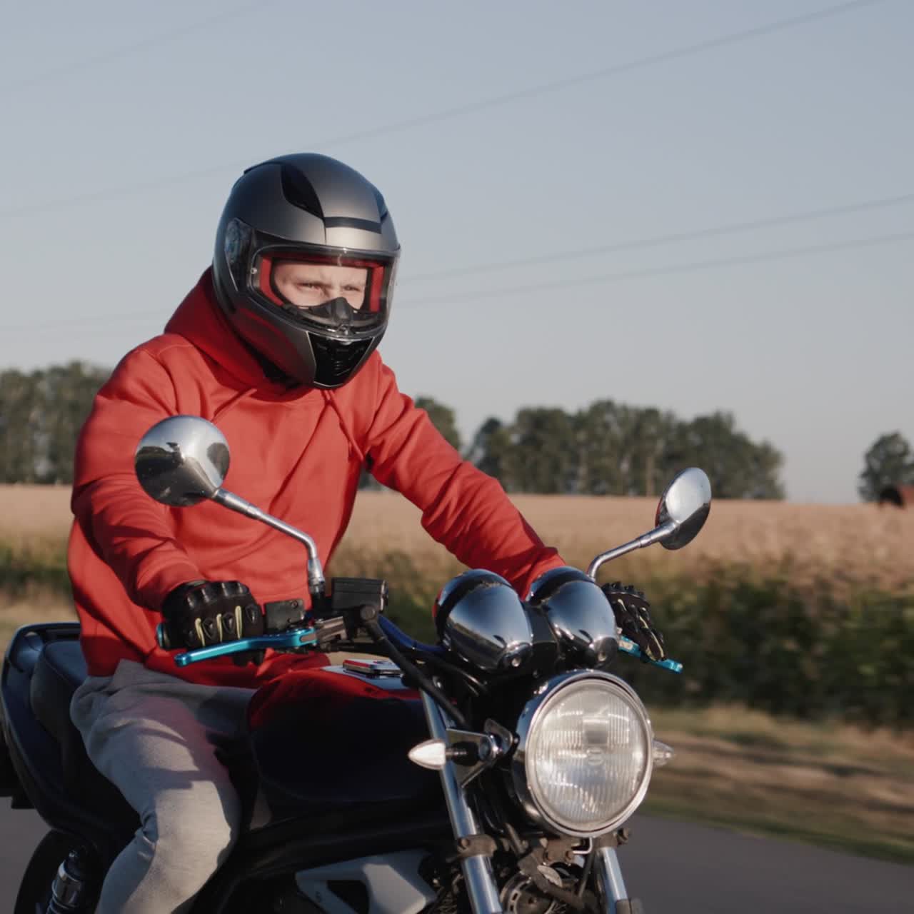 Un giovane guida una moto lungo i campi di mais 1