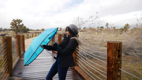 a pretty hispanic woman opening a broken umbrella in slow motion and laughing during a rain storm in bad weather