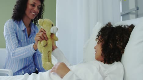 front view of african american mother giving teddy bear to her son in the ward at hospital 4k