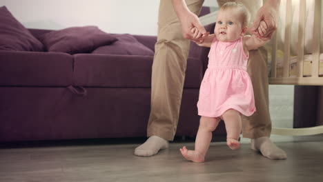 First-step-in-life.-Beautiful-baby-girl-stand-up-with-father-support