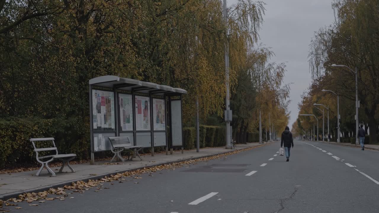 A video frame captures a solitary figure walking down an empty, tree-lined street from a low angle
