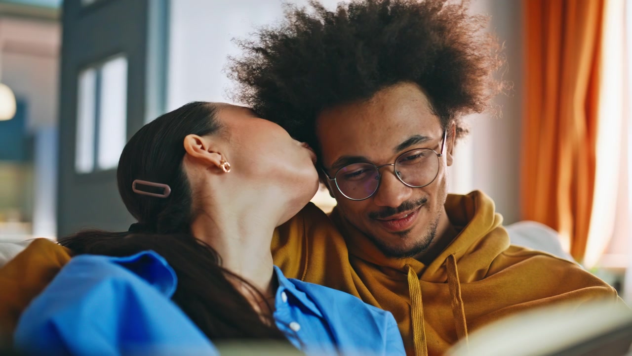 Close-up de casal inter-racial olhando um álbum de fotos em um momento aconchegante em casa