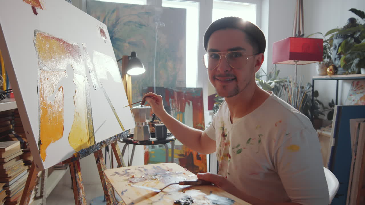 Retrato de artista masculino alegre pintando en un estudio