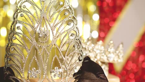 a master jeweler checks a beauty pageant winner's diamond tiara - bokeh blurred background with gown and sash