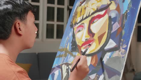 Side View Of An Asian Artist Boy Holding Paintbrush Mixed Colour And Thinking Before Painting A Girl'S Face On The Canvas