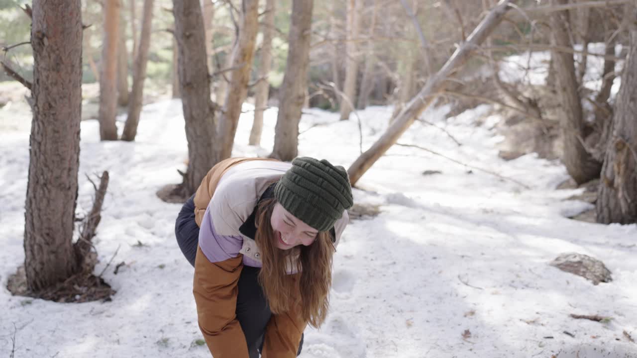 Woman having a snowball fight in the forest